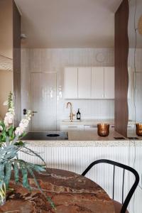eine Küche mit weißen Schränken und einem Tisch mit Stühlen in der Unterkunft Vintage Glamour Suite, parveke, parkkipaikka in Helsinki