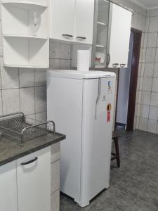 a white refrigerator in a kitchen with white cabinets at Casa com dois quartos,dois banheiros,sendo uma suíte,sala de estar cozinha e garagem in Poços de Caldas