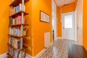 a hallway with orange walls and wooden shelves filled with books at Vibrant and Spacious 2BD flat for 4 in Edinburgh in Edinburgh
