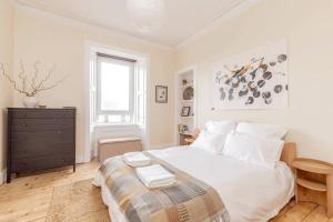 a white bedroom with a bed and a window at Vibrant and Spacious 2BD flat for 4 in Edinburgh in Edinburgh