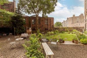 a garden with a wooden bench in front of a building at Vibrant and Spacious 2BD flat for 4 in Edinburgh in Edinburgh