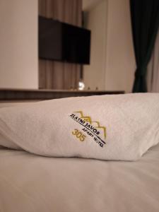 a pillow on a bed with a hotel logo on it at Apartman 305 Zlatni Javor in Jahorina