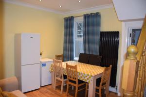 a kitchen with a table and a white refrigerator at Three Bedroom House Lancaster Road in London