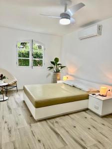 - une chambre blanche avec un grand lit et un ventilateur dans l'établissement Apartamento estilo Chalé com piscina, à Ubatuba