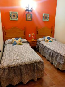 - 2 lits dans une chambre aux murs orange dans l'établissement Cabaña 2 Ventorrillo, à Riópar