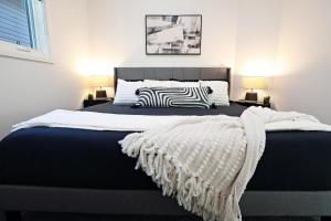 ein Bett mit einer schwarzen und weißen Bettdecke und zwei Lampen in der Unterkunft Three King Beds,Central A/C,Fireplace,Park,Disney+ in Edmonton