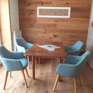 a dining room with a wooden table and blue chairs at Landcafe SIMA & Zimmervermietung in Forheim
