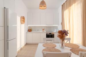 een keuken met een tafel en 2 stoelen en een keuken met witte kasten bij SeaView Apartment 2 in Samos
