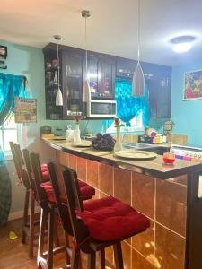 eine Küche mit einer Bar mit Stühlen und einer Arbeitsplatte in der Unterkunft Island style home, low key rental in Roatán