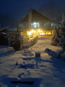 un patio cubierto de nieve frente a una casa por la noche en Beli Kamen etno selo, en Prokuplje