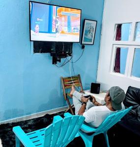 un hombre sentado en una silla viendo una tele en Makako Chillout Hostel, en Cartagena de Indias