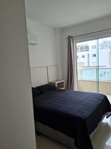 um quarto com uma cama e uma grande janela em Amplo e aconchegante apartamento com 3 quartos a 50m da praia de Bombas em Bombinhas