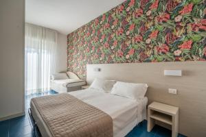 リミニにあるLotus Hotel ALL INCLUSIVE & SPIAGGIAのベッド付きの客室で、壁には絵画が飾られています。