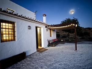 une maison blanche avec une terrasse couverte et une lune dans le ciel dans l'établissement Casa Rural “Los Campos”, à Almogía
