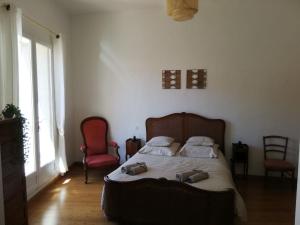 1 dormitorio con 1 cama, 2 sillas y ventana en Maison de caractère avec jacuzzi entre mer et montagne à Espira de Conflent en Espira-de-Conflent