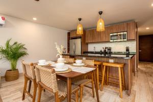 an open kitchen with a wooden table and chairs at Luxury Stay at AWA Playacar 3BR Designer Condo in Playa del Carmen