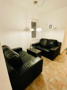 a living room with two black leather couches and a table at Riverhouse apartment in Radovljica