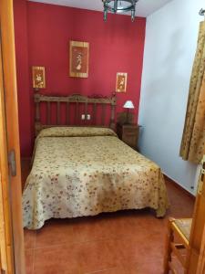 a bedroom with a bed in a red wall at El Ventorrillo 1 in Riópar