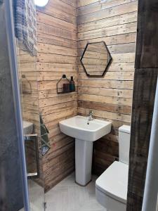 a bathroom with a white sink and wooden walls at Honeysuckle Straw Bale Cabin in Dallas