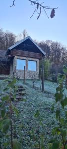 a stone building with two windows in a field at Vikendica Volar in Prijedor