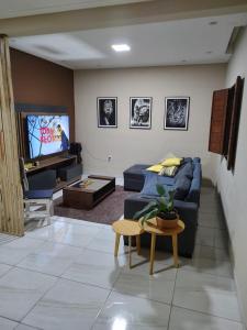 ein Wohnzimmer mit einem blauen Sofa und einem TV in der Unterkunft Casa com piscina in Camaçari