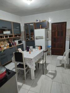 y cocina con mesa, sillas y nevera. en Casa com piscina, en Camaçari