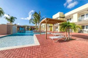 a patio with a swimming pool and a resort at Affordable family apartment only 350 yards from Eagle Beach in Palm-Eagle Beach