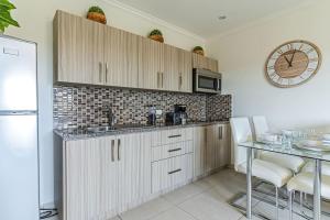 a kitchen with white cabinets and a table and a clock at Affordable family apartment only 350 yards from Eagle Beach in Palm-Eagle Beach +15 photos