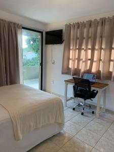 Itacaré Flats في إيتاكاري: غرفة نوم مع سرير ومكتب مع الكمبيوتر المحمول