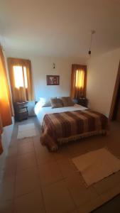 1 dormitorio con 1 cama y 2 ventanas en El paraíso farmhouse en Cholila