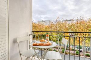 un balcón con una mesa con un plato de comida y 2 sillas en L'industriel - 2'mn du métro - aux portes de Paris, en Saint-Mandé