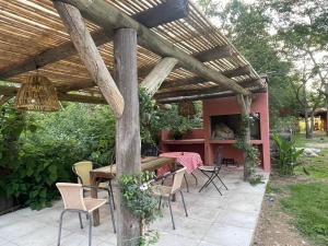 un patio con mesa y sillas bajo una pérgola de madera en El campito en Capilla del Señor