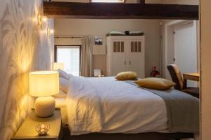 - une chambre avec un grand lit blanc et une lampe dans l'établissement La Bergerie, à Leuze-en-Hainaut