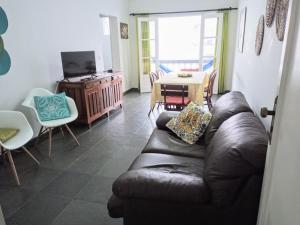 a living room with a leather couch and a table at apartamento fofo Astúrias in Guarujá