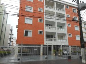 un edificio de ladrillo rojo con balcones blancos. en apartamento fofo Astúrias en Guarujá