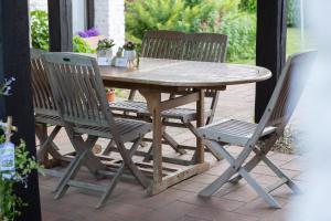 Une table et des chaises en bois sont disponibles sur la terrasse. dans l'établissement La Bergerie, à Leuze-en-Hainaut