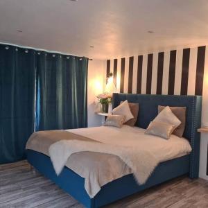 uma cama azul num quarto com cortinas azuis em L’Appar(T) du Grand Bois - Jacuzzi - em Soucelles