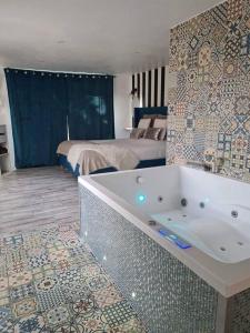 - Baño con bañera en un dormitorio con cama en L’Appar(T) du Grand Bois - Jacuzzi -, en Soucelles