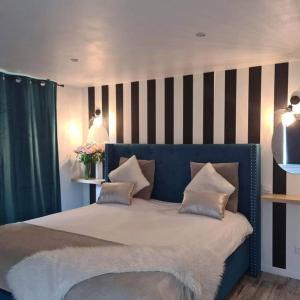 Dormitorio con cama azul y pared a rayas en L’Appar(T) du Grand Bois - Jacuzzi -, en Soucelles
