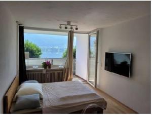 a bedroom with a bed and a large window at Seeapartment am Ossiacher See am Fuße der Gerlitzen in Stiegl