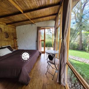 ein Schlafzimmer mit einem Bett und einem Tisch auf einem Holzboden in der Unterkunft Exclusivo Cocora con Jacuzzi Salento Quindio in Salento