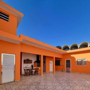 un bâtiment orange avec une terrasse et une table dans l'établissement No Centro a 3 min da praia, Pet Friendly e Wi Fi, à Peruíbe