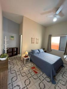 Un dormitorio con una cama azul y una ventana en No Centro a 3 min da praia, Pet Friendly e Wi Fi, en Peruíbe