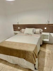 アルカラ・デ・エナレスにあるSueña en la Plaza Cervantes 3のベッドルーム1室(大型ベッド1台、木製ヘッドボード付)