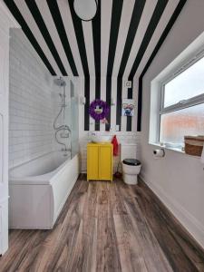 a bathroom with a white tub and a yellow cabinet at Eclectic 1BD in the Heart of Cheltenham! in Cheltenham