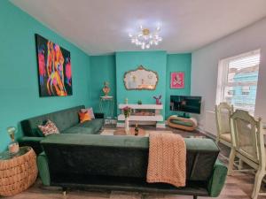 ein Wohnzimmer mit einem grünen Sofa und einem TV in der Unterkunft Eclectic 1BD in the Heart of Cheltenham! in Cheltenham