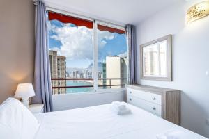 a bedroom with a window with a view of the city at Don Miguel 4-F Apartment Levante Beach in Benidorm +25 photos