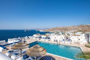 Elle offre une vue sur la piscine bordée de chaises et de parasols. dans l'établissement Hotel Tagoo, à Mykonos