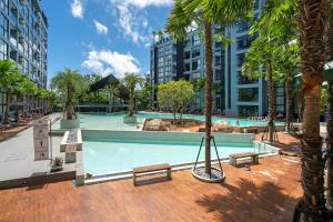 カマラビーチにあるPartial Seaview Condo Kamala Beachの市街のヤシの木とベンチのあるスイミングプール