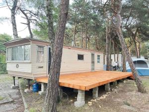 赫爾的住宿－Your Caravan Hel，树林中的一个小房子,有木甲板